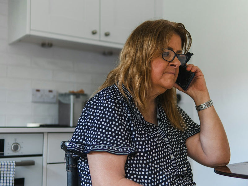 Woman talking on a cordless phone in her kitchen