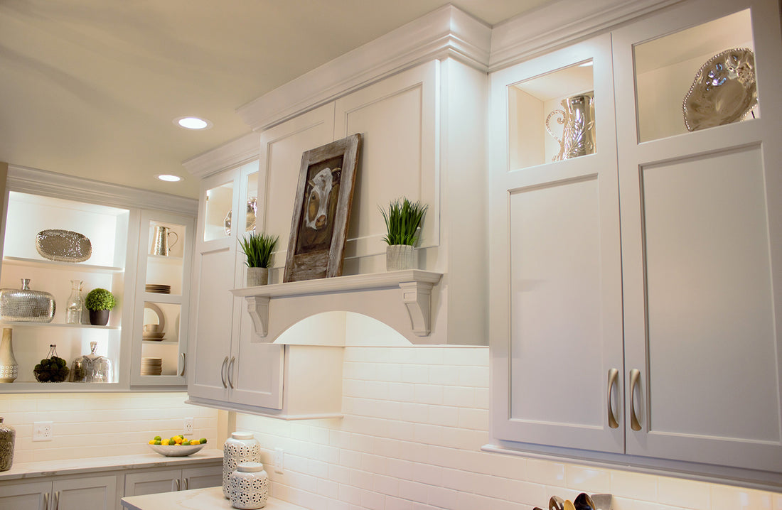 White kitchen cabinets lit with LED tape light under the cabinets and inside glass doors